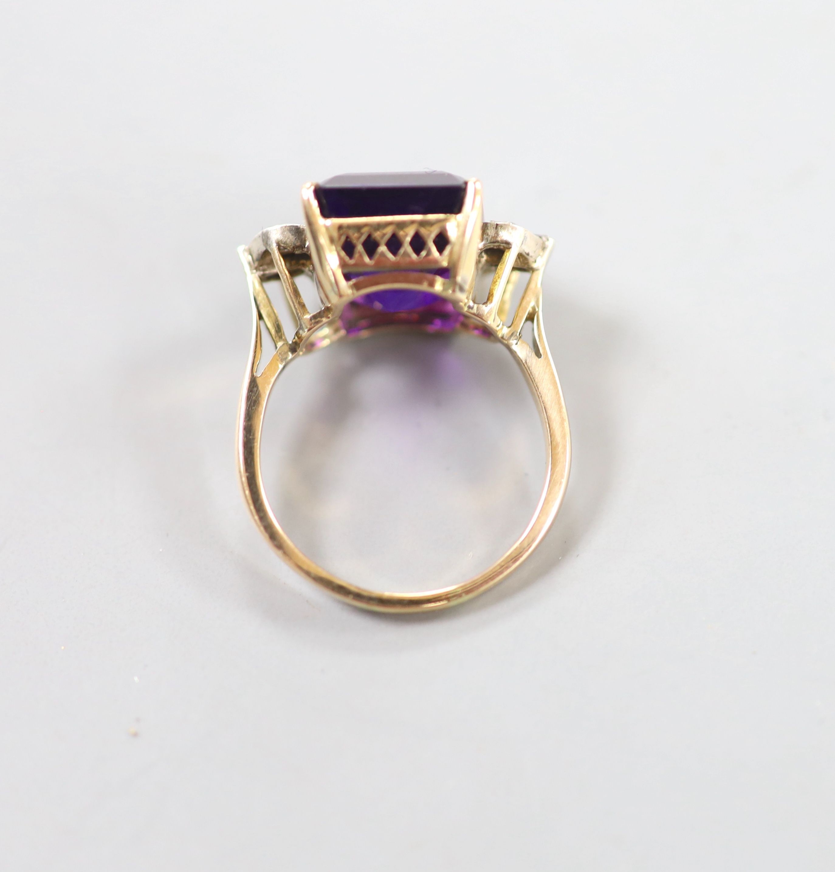 A yellow metal and single stone emerald cut amethyst dress ring, with trapeze and round cut diamond set shoulders, size P, gross weight 6.1 grams.